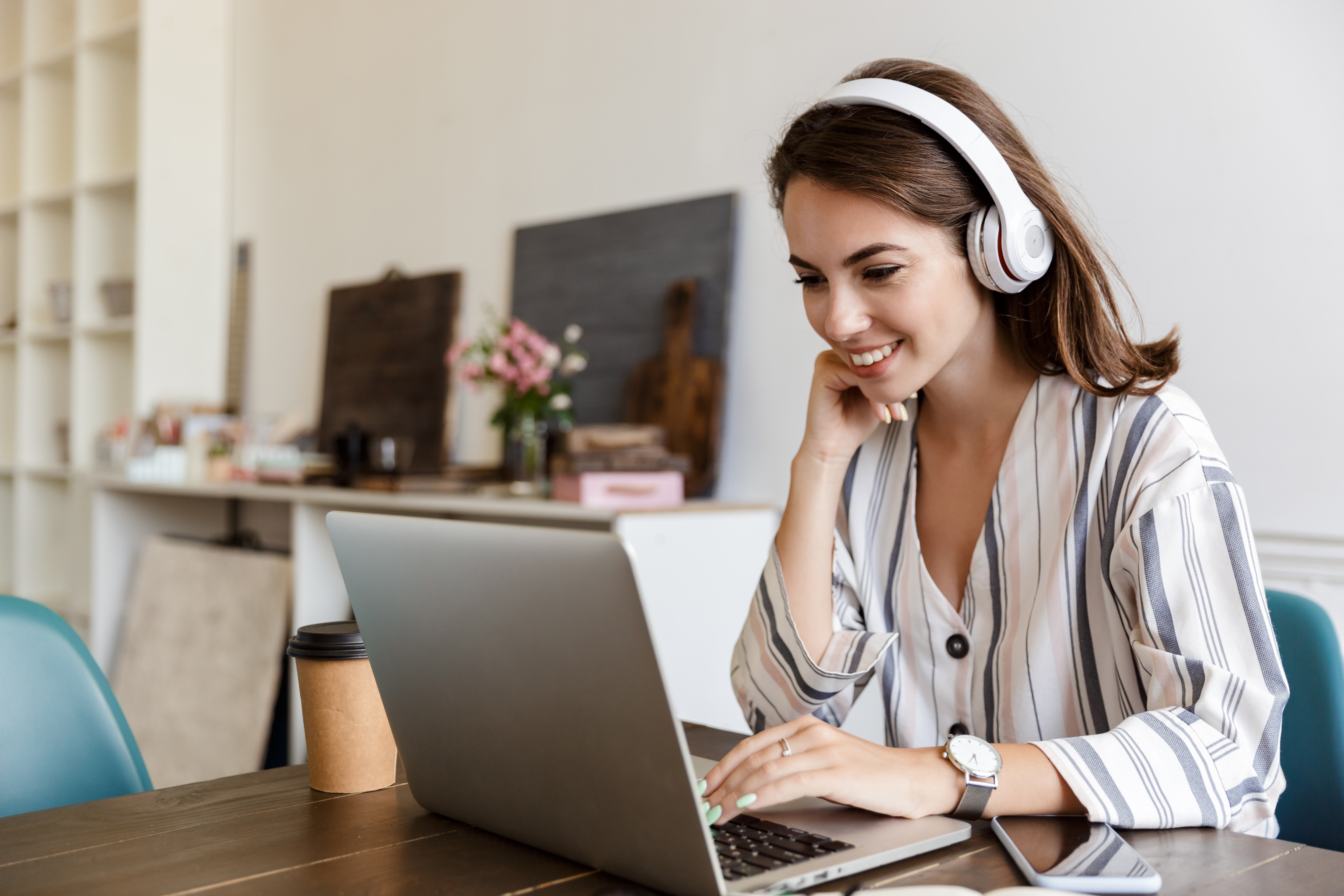 Young woman with headphones reading about the benefits of CIPD membership on her laptop