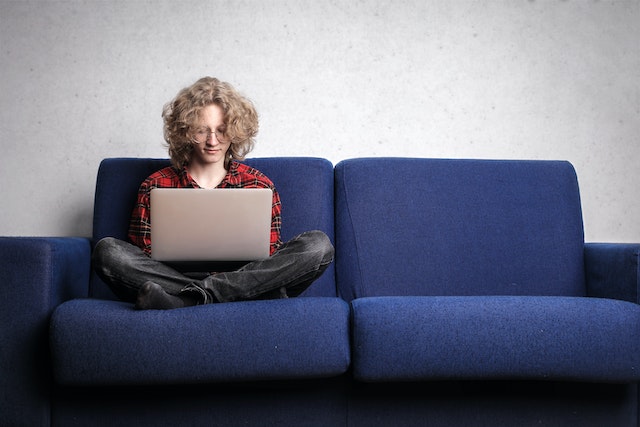 A woman sat on a sofa working on a laptop