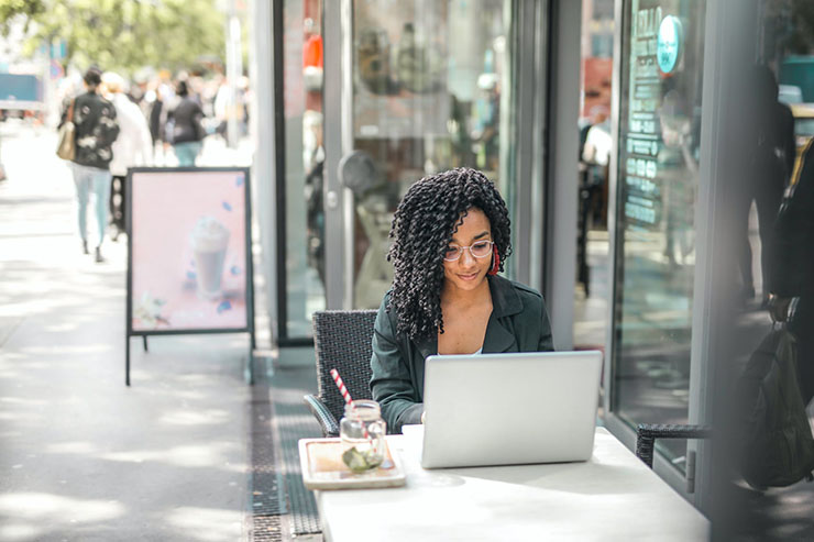 Woman Working Outside Cafe On Laptop