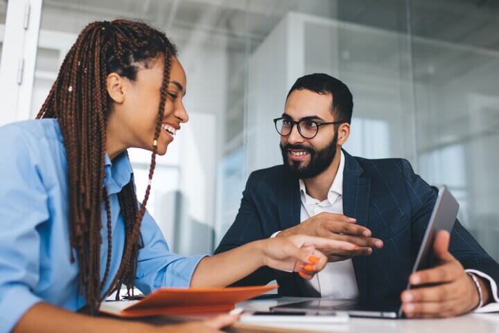 Two colleagues looking at laptop together in office environment